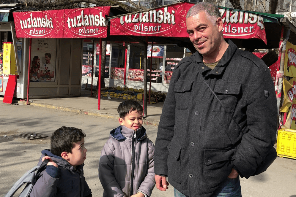 Ein Mann steht mit seinen zwei Söhnen an einer Busstation in Tuzla, Bosnien: Die Familie versucht, nach Frankreich zu gelangen.