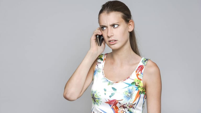 Eine genervte Frau am Telefon: Vorsicht vor Spamanrufen.