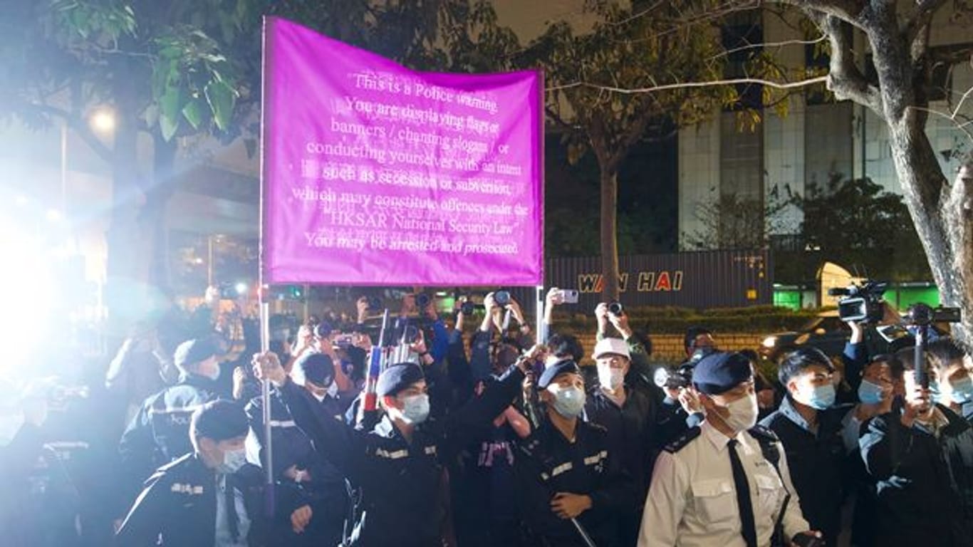 Polizisten hissen vor einem Gericht in Hongkong eine Warnflagge gegen die Unterstützer von 47 pro-demokratischen Aktivisten, die wegen angeblicher Verstöße gegen das neue Sicherheitsgesetz vorerst in Untersuchungshaft bleiben müssen.