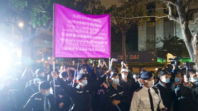 Polizisten hissen vor einem Gericht in Hongkong eine Warnflagge gegen die Unterstützer von 47 pro-demokratischen Aktivisten, die wegen angeblicher Verstöße gegen das neue Sicherheitsgesetz vorerst in Untersuchungshaft bleiben müssen. Polizisten hissen vor einem Gericht in Hongkong eine Warnflagge gegen die Unterstützer von 47 pro-demokratischen Aktivisten, die wegen angeblicher Verstöße gegen das neue Sicherheitsgesetz vorerst in Untersuchungshaft bleiben müssen.