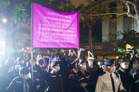 Polizisten hissen vor einem Gericht in Hongkong eine Warnflagge gegen die Unterstützer von 47 pro-demokratischen Aktivisten, die wegen angeblicher Verstöße gegen das neue Sicherheitsgesetz vorerst in Untersuchungshaft bleiben müssen.