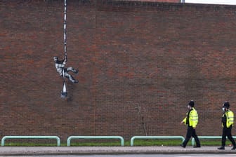 Polizisten gehen vor einem Wandgemälde des Streetart-Künstlers Banksy an der Mauer eines ehemaligen Gefängnisses.