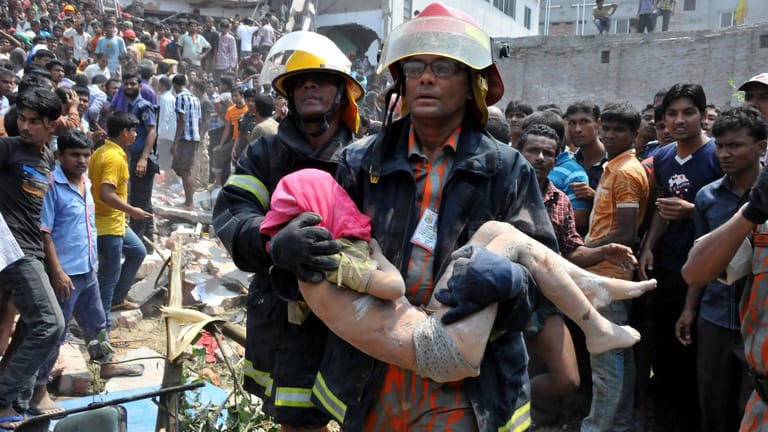 24. April 2013: Ein Helfer trägt einen verletzten Jungen aus dem Schutt nach dem Unglück von Rana Plaza. Tausende Menschen suchen nach ihren Angehörigen.