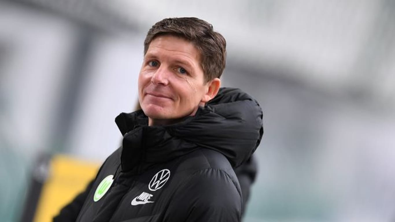 Wolfsburgs Trainer Oliver Glasner lächelt in die Kamera eines Fotografen.