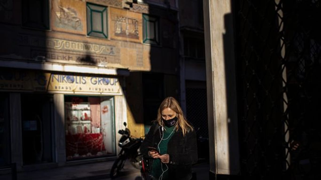 Eine Frau, die eine schützende Gesichtsmaske trägt, geht im Zentrum von Athen.