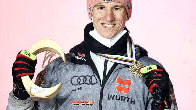 Karl Geiger posiert bei der Siegerehrung mit der Bronzemedaille.