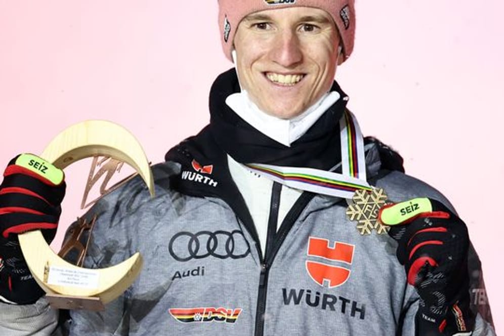 Karl Geiger posiert bei der Siegerehrung mit der Bronzemedaille.