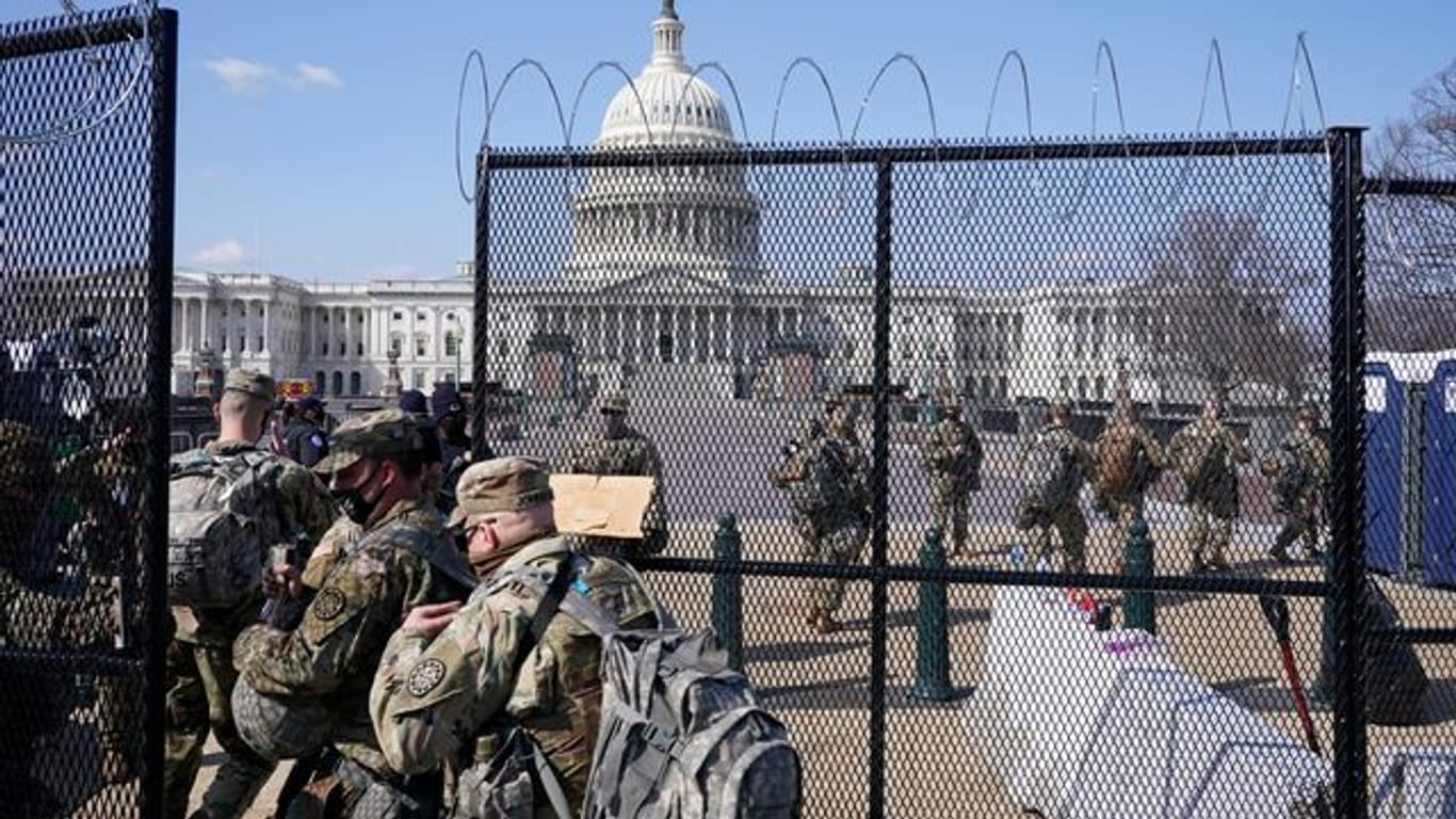 Soldaten der Nationalgarde gehen durch das Tor eines Sicherheitszauns vor dem Kapitol.