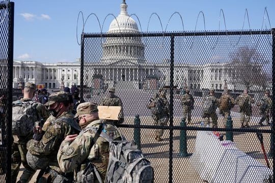Soldaten der Nationalgarde gehen durch das Tor eines Sicherheitszauns vor dem Kapitol.