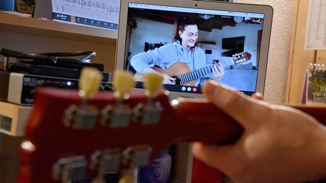Ein Gitarrenlehrer unterrichtet eine Schülerin via Online-Videokonferenz. Ein Gitarrenlehrer unterrichtet eine Schülerin via Online-Videokonferenz.