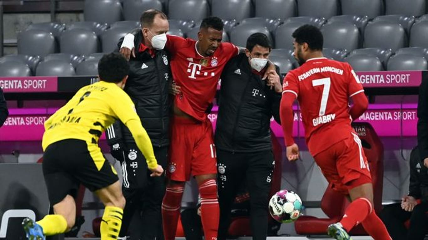 Münchens Abwehrspieler Jerome Boateng (M) wird verletzt vom Platz geführt.