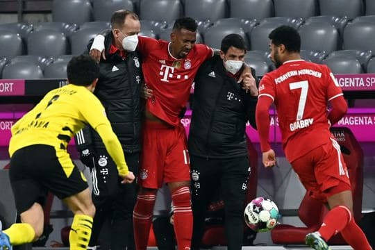 Münchens Abwehrspieler Jerome Boateng (M) wird verletzt vom Platz geführt.
