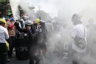 Anti-Putsch-Demonstranten entladen Feuerlöscher, um während einer Demonstration in Mandalay den Auswirkungen des von der Polizei abgefeuerten Tränengases entgegenzuwirken.