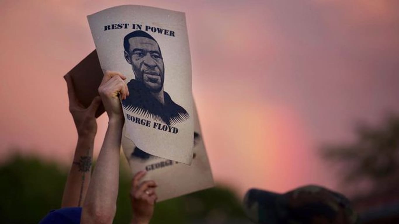 Demonstranten halten während eines Protestes ein Porträt von George Floyd in die Höhe.