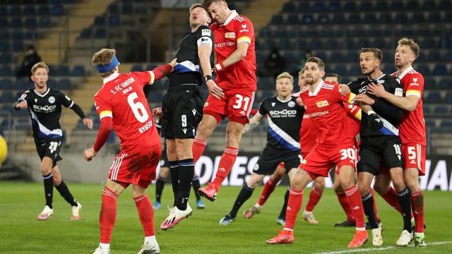 Bielefelds Stürmer Fabian Klos (M, l) und Unions Abwehrspieler Robin Knoche (M, r) liefern sich ein Kopfballduell im Strafraum der Berliner.