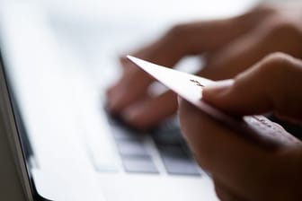 Ein Nutzer mit Kreditkarte am Rechner (Symbolbild): Banken fragen per Mail niemals nach sensiblen Konto-, Kreditkarten- oder Zugangs-Informationen, geschweige denn nach persönlichen Daten.