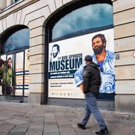 Ein Mann geht an einer Hausfassade vorbei, in deren Fenster Zeichnungen von Bud Spencer, zu sehen sind: Berlin bekommt ein Bud-Spencer-Museum.