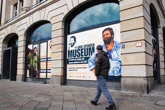 Ein Mann geht an einer Hausfassade vorbei, in deren Fenster Zeichnungen von Bud Spencer, zu sehen sind: Berlin bekommt ein Bud-Spencer-Museum.