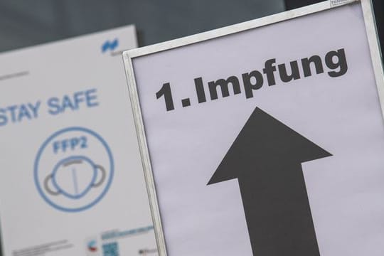 Ein Schild auf einem Messegelände weist den Weg zu einem Impfzentrum.