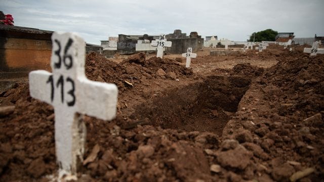 Ein einfaches Kreuz ohne Namen und mit einer Nummer steht an einem offenen Grab am Friedhof von Iraja in Rio de Janeiro.