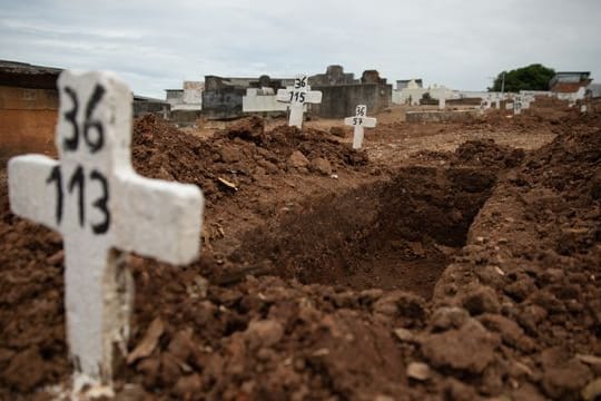 Ein einfaches Kreuz ohne Namen und mit einer Nummer steht an einem offenen Grab am Friedhof von Iraja in Rio de Janeiro.