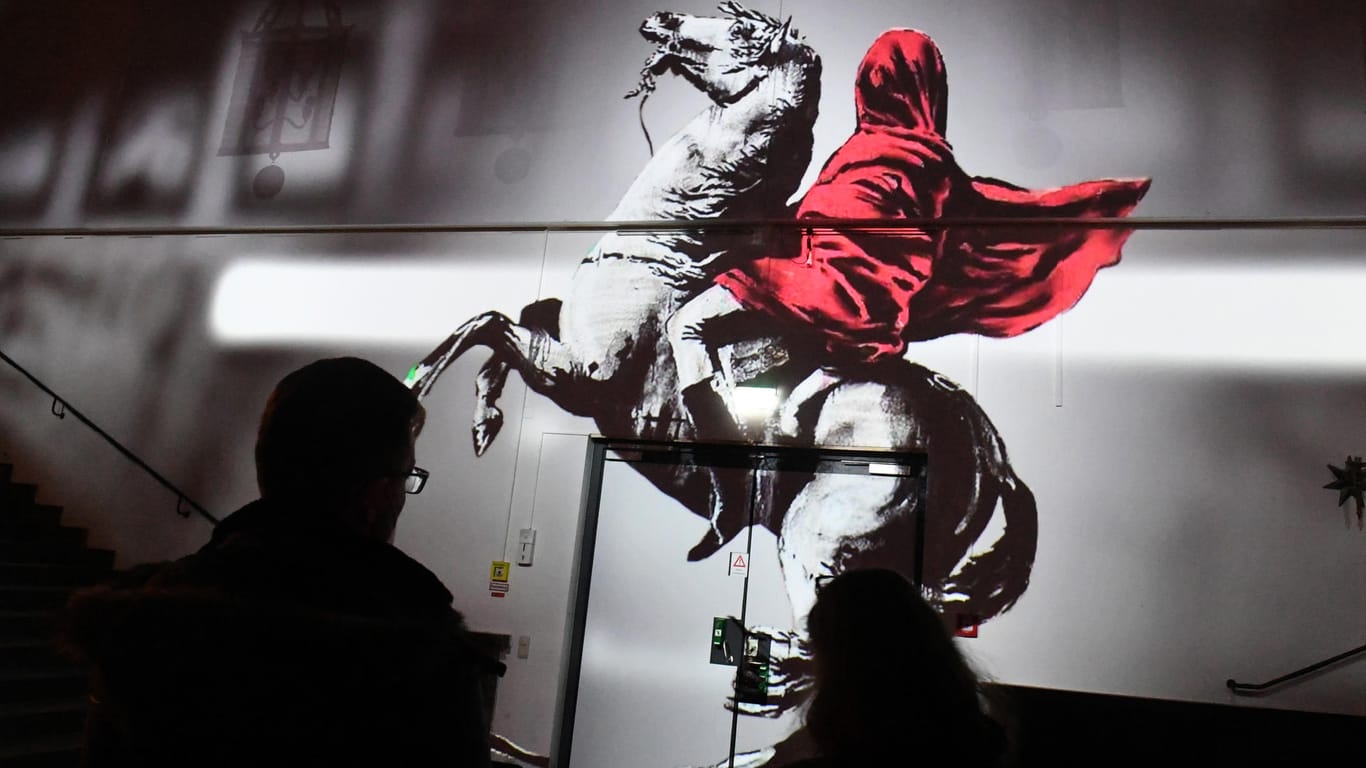 Besucher betrachten in der Ausstellung "The Mystery of Banksy – A Genius Mind" eine Videoprojektion: Die Schau im Isarforum im Deutschen Museum zeigt vorwiegend Reproduktionen und nur ganz wenige Originale.