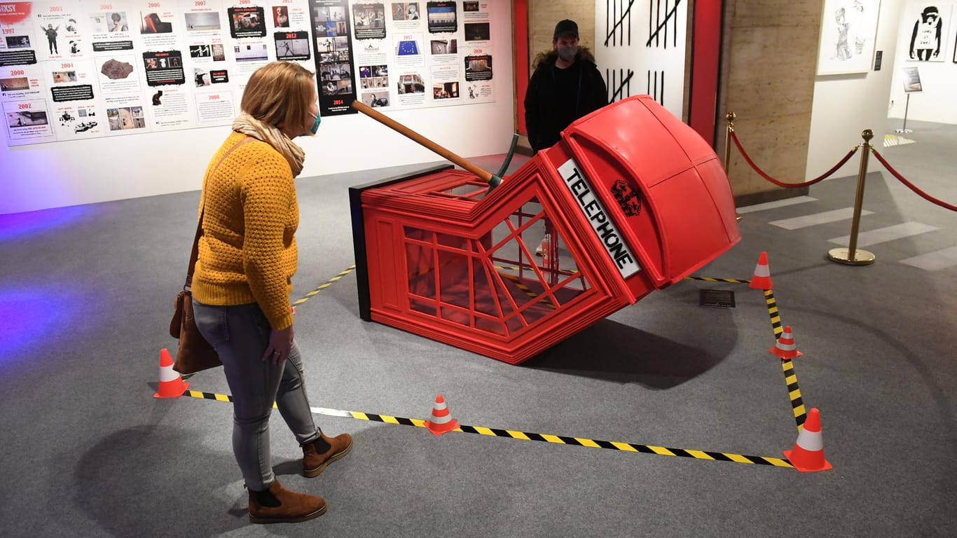 Eine Besucherin betrachten ein Kunstwerk: Die Banksy Ausstellung darf in München am 10. März 2021 eröffnen.