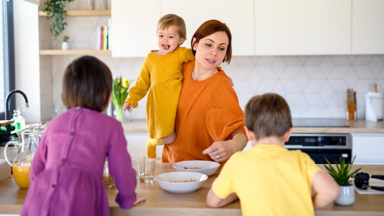 Eine Mutter macht ihren drei Kindern Frühstück (Symbolbild): Sorgearbeit ist auch Arbeit, wird aber nicht entlohnt.