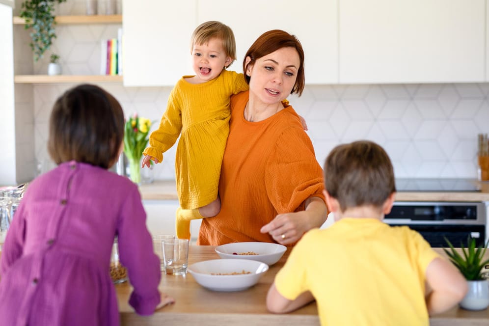 Eine Mutter macht ihren drei Kindern Frühstück (Symbolbild): Sorgearbeit ist auch Arbeit, wird aber nicht entlohnt.