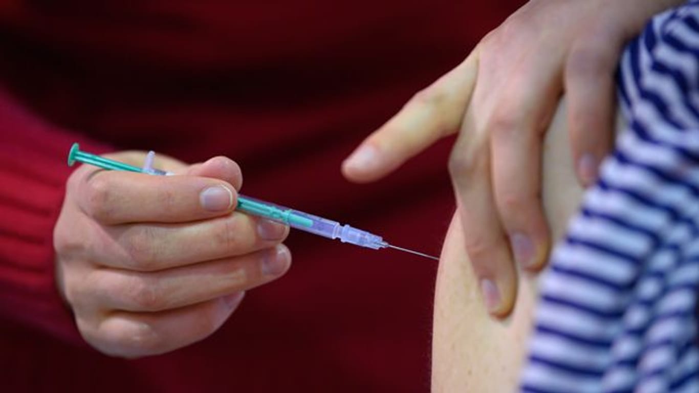Eine Mitarbeiterin eines Impfzentrums impft eine Frau