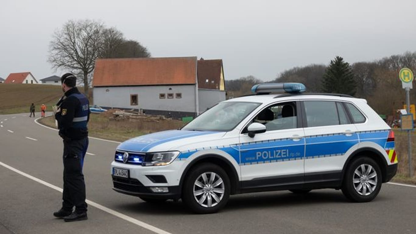 Ein Polizist sperrt mit einem Streifenwagen eine Straße in Weilerbach.