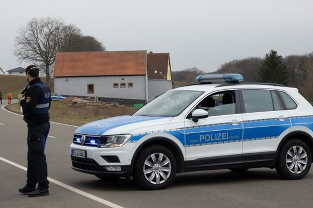 Ein Polizist sperrt mit einem Streifenwagen eine Straße in Weilerbach.