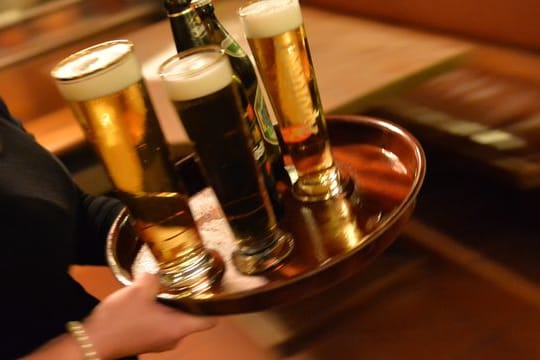 Eine Bedienung trägt in einem Lokal ein Tablett mit Bier