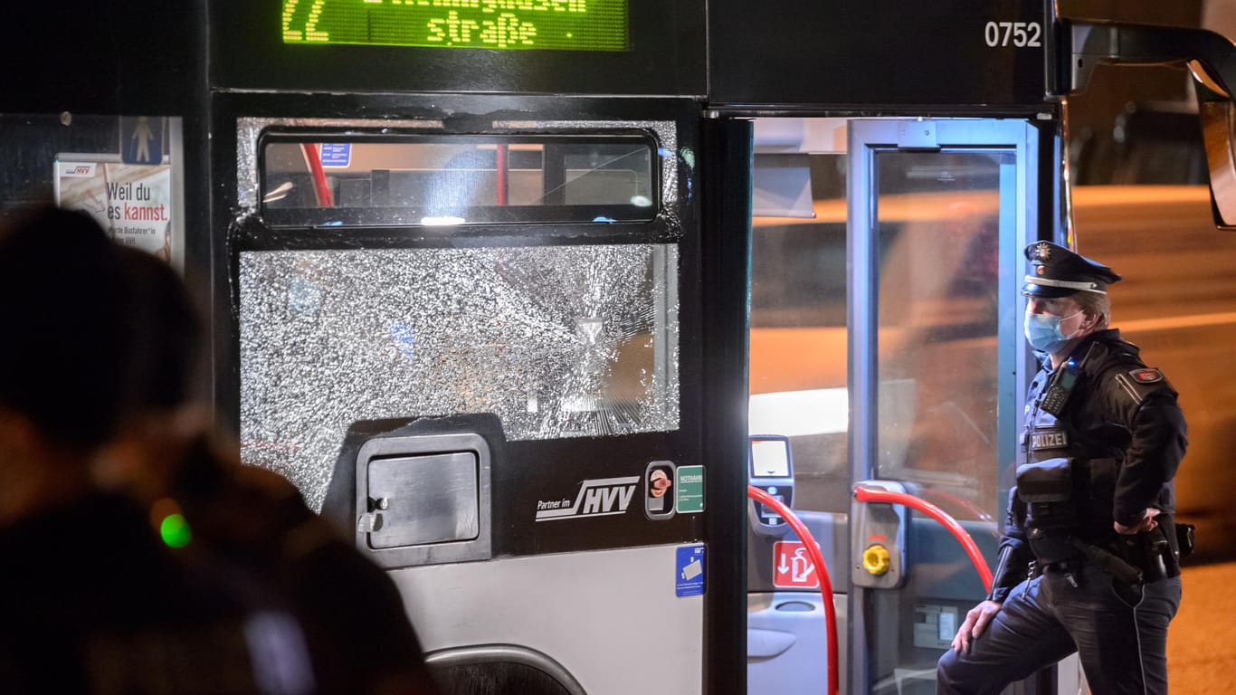 Polizisten stehen an dem Bus mit der beschädigten Scheibe: Es konnte zunächst nicht ausgeschlossen werden, dass ein Projektil die Scheibe beschädigt hatte.