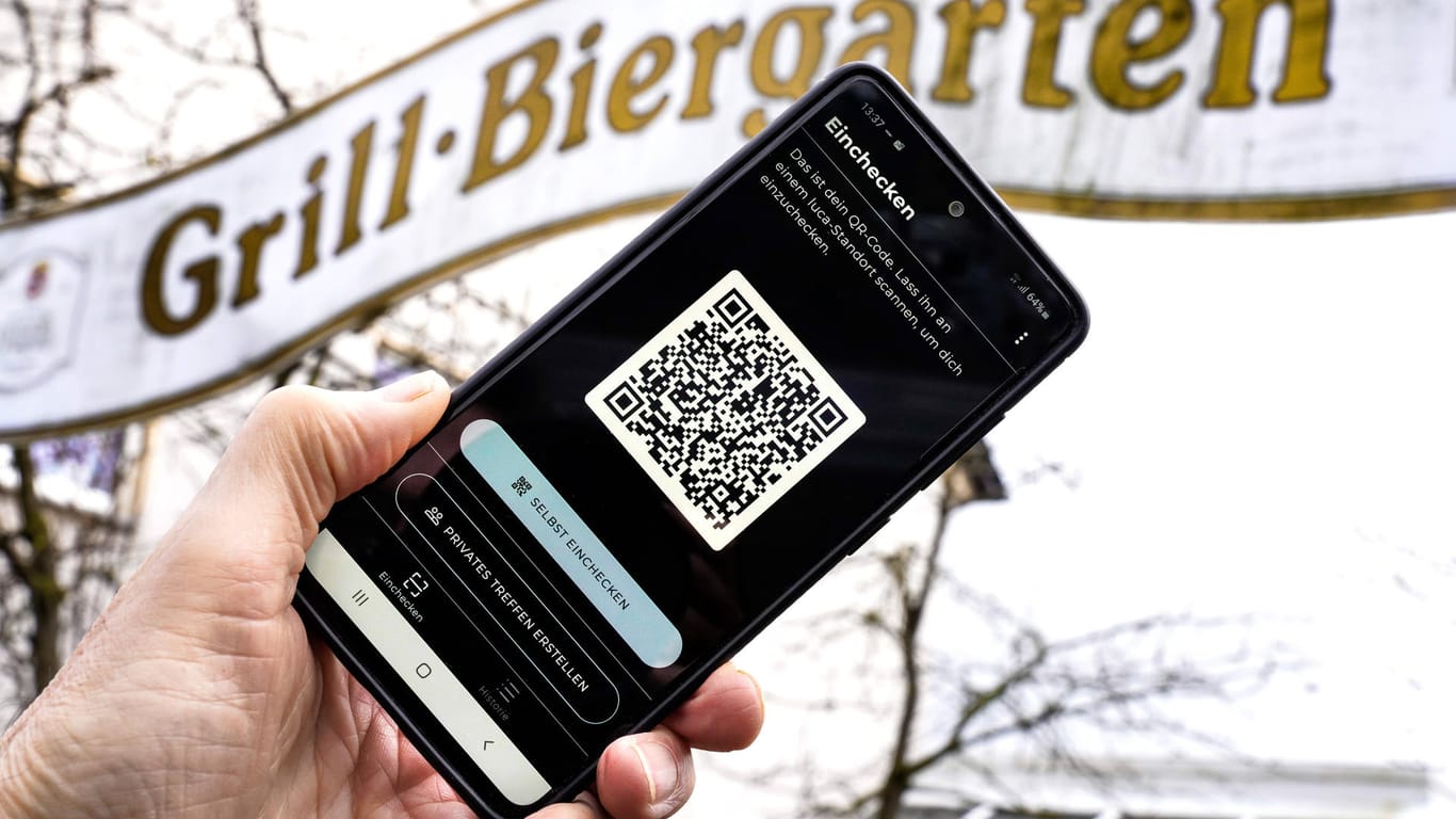 Die Luca-App mit QR-Code auf einem Smartphone vor einem Biergarten-Schild (Symbolbild): Die App könnte eine digitale und einheitliche Lösung der Kontaktnachverfolgung sein.