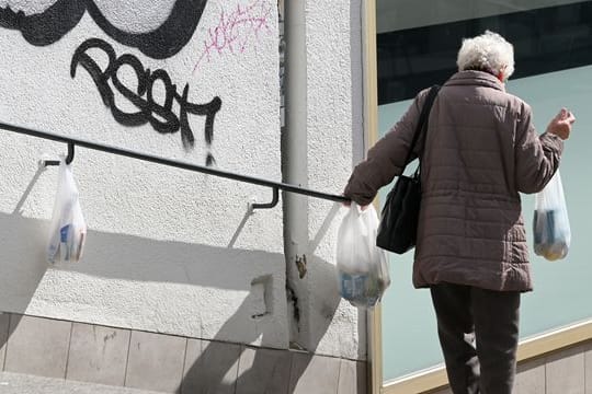 Die Pandemie verschärft die soziale Ungleichheit - manch einer ist auf die Hilfe von Fremden angewiesen, wie hier eine Frau an einem Gabengeländer.