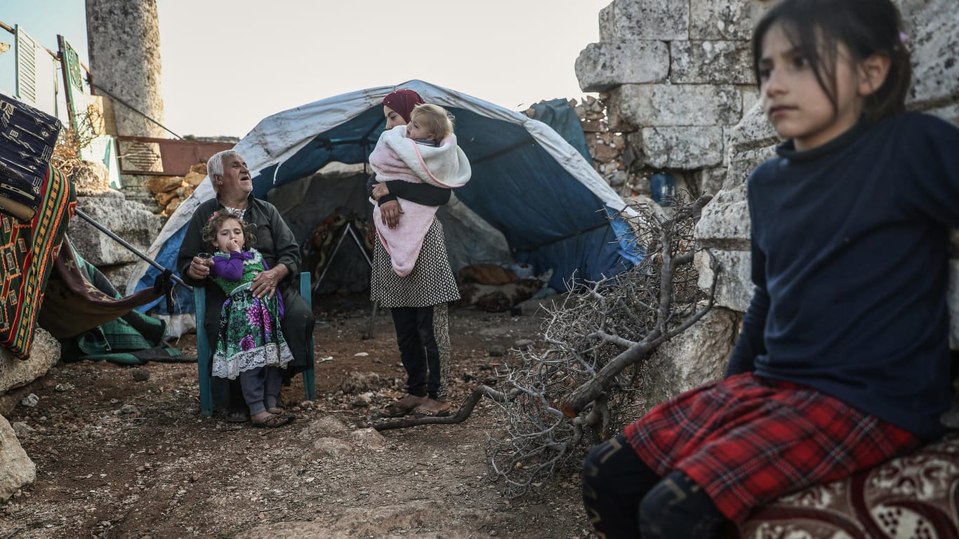 Eine vertriebene syrische Familie sitzt in den Ruinen einer alten Dorfkirche: Viele Eltern wissen nicht mehr wie sie ihre Kinder versorgen sollen.