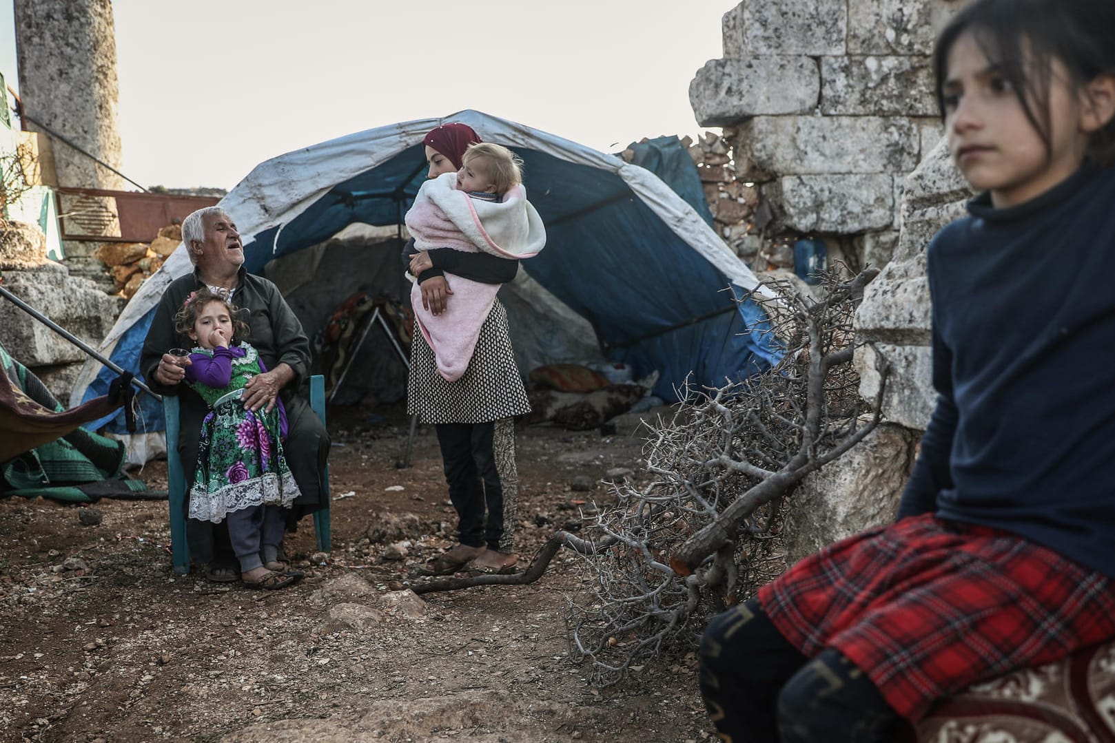 Eine vertriebene syrische Familie sitzt in den Ruinen einer alten Dorfkirche: Viele Eltern wissen nicht mehr wie sie ihre Kinder versorgen sollen.