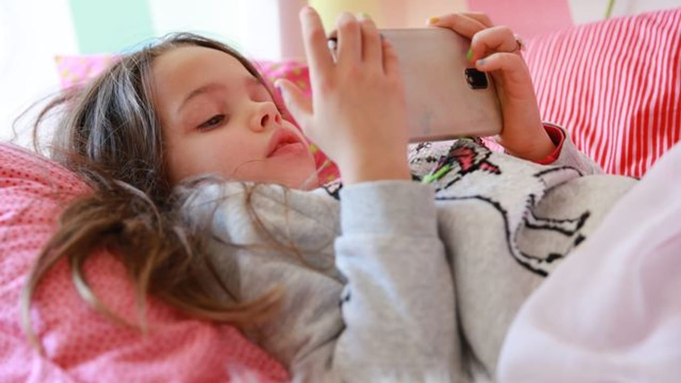 Ein Kind spielt am Smartphone (Symbolbild): Um teure In-App-Käufe zu verhindern, sollten die richtigen Einstellungen ausgewählt werden.