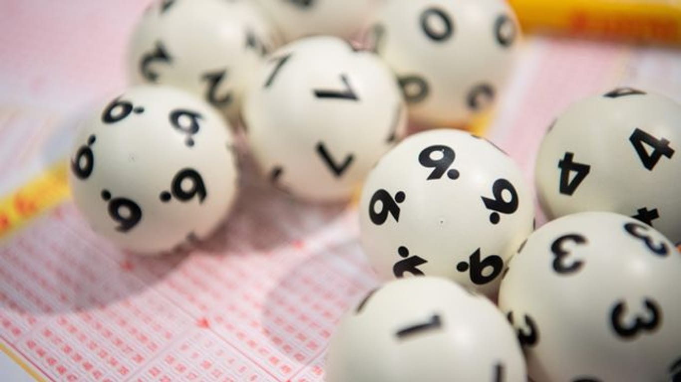 Lotto-Kugeln liegen auf einem Lottoschein: In England hat ein Paar den Jackpot geknackt, dann aber doch kein Geld erhalten.