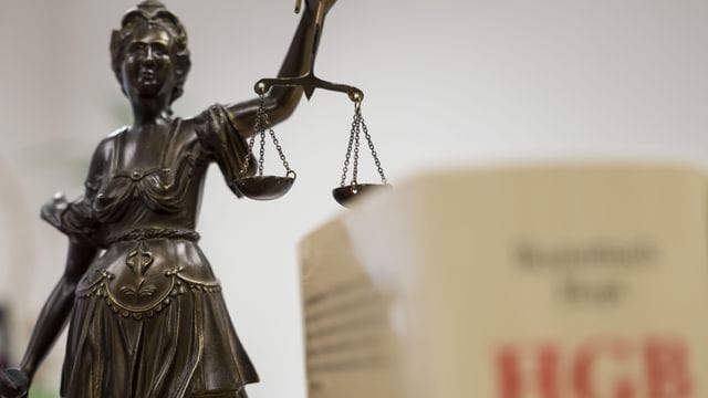 Eine Statue der Justitia hält eine Waage in ihrer Hand