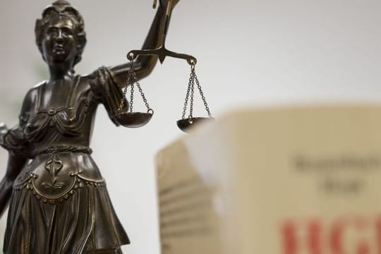 Eine Statue der Justitia hält eine Waage in ihrer Hand