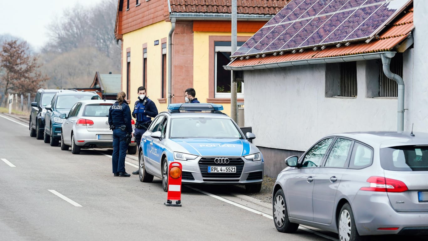 Polizisten vor dem Tatort in Weilerbach: Wie lange der Mann mit den Leichen unter einem Dach schlief, ist noch unklar.