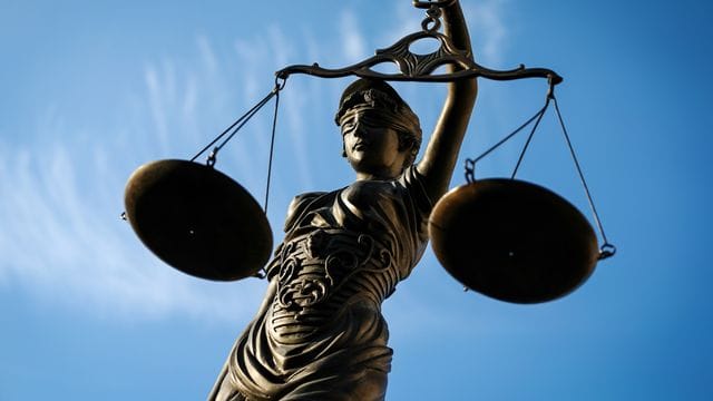 Eine Statue der Justitia hält eine Waage in ihrer Hand (Symbolbild): Weil er Dienstgeheimnisse weitergeleitet haben soll, muss sich ein Polizist in Düsseldorf verantworten.