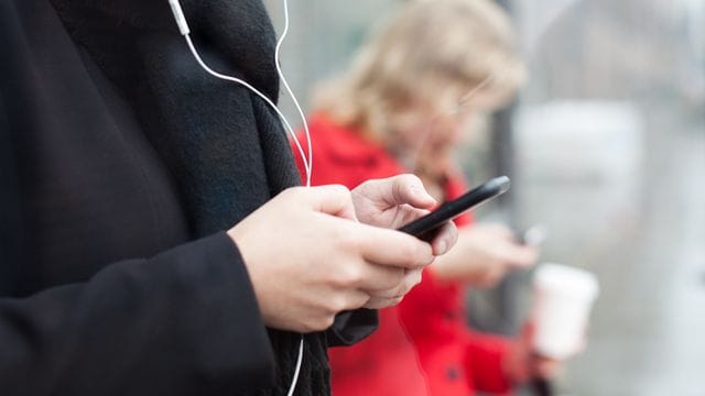 Menschen, die auf Smartphones starren (Symbolbild): Wann wird der Griff zum Handy zur Sucht?