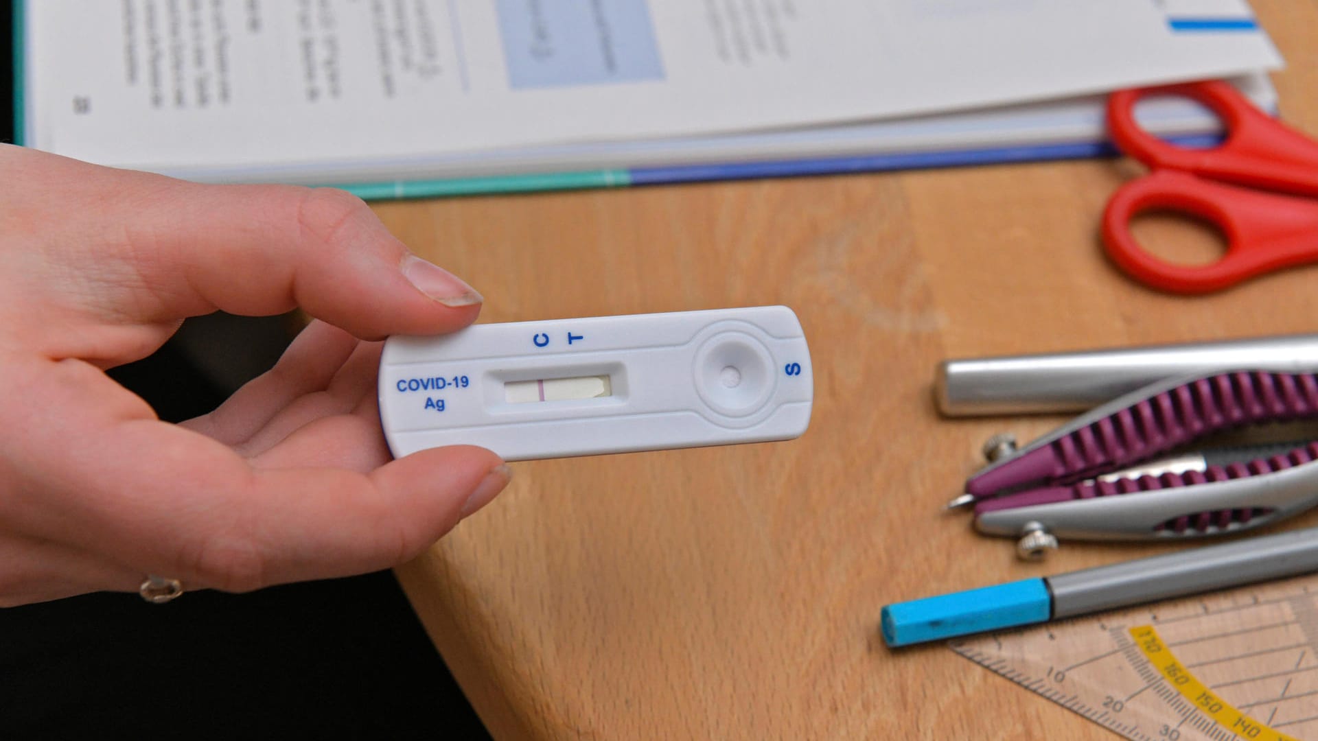 Eine Schülerin hält einen Schnelltest in der Hand (Symbolbild): Wann die Kölner Schüler solche Tests erhalten, ist noch nicht klar. Feststeht, dass am Montag der Präsenzunterricht wieder beginnt.