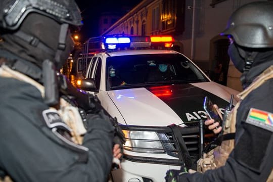 Schwerbewaffnete Polizisten bewachen zwei ehemalige Minister auf ihrem Weg zur Aussage.