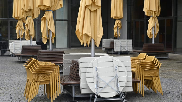 Gestapelte Stühle und Tische vor einem Münchner Restaurant (Archivbild): Während die Betriebe ruhen, werden die Wirtschaftshilfen für Gastronomen nur schleppend ausgezahlt.