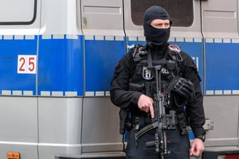 Ein Polizist steht schwer bewaffnet vor einem Mannschaftswagen: Corona-Hilfen sollen an Islamisten geflossen sein – eine Viertel Million wurde wieder eingezogen.