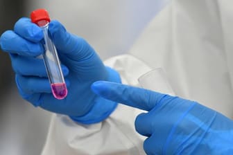 Eine Laborantin hält einen Corona-Test in der Hand